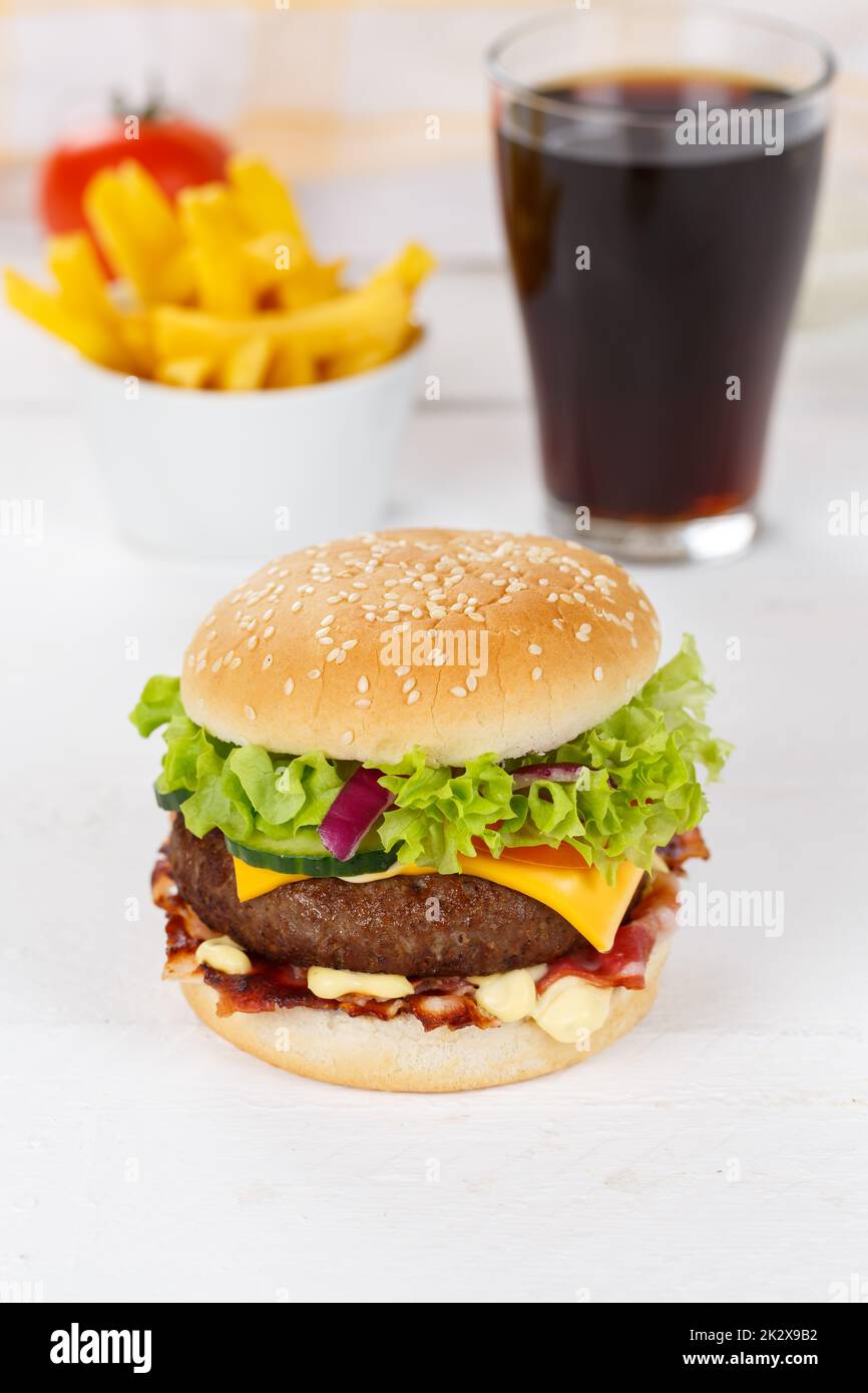 Hamburger Cheeseburger meal fastfood fast food with cola drink and French Fries on a wooden board portrait format Stock Photo
