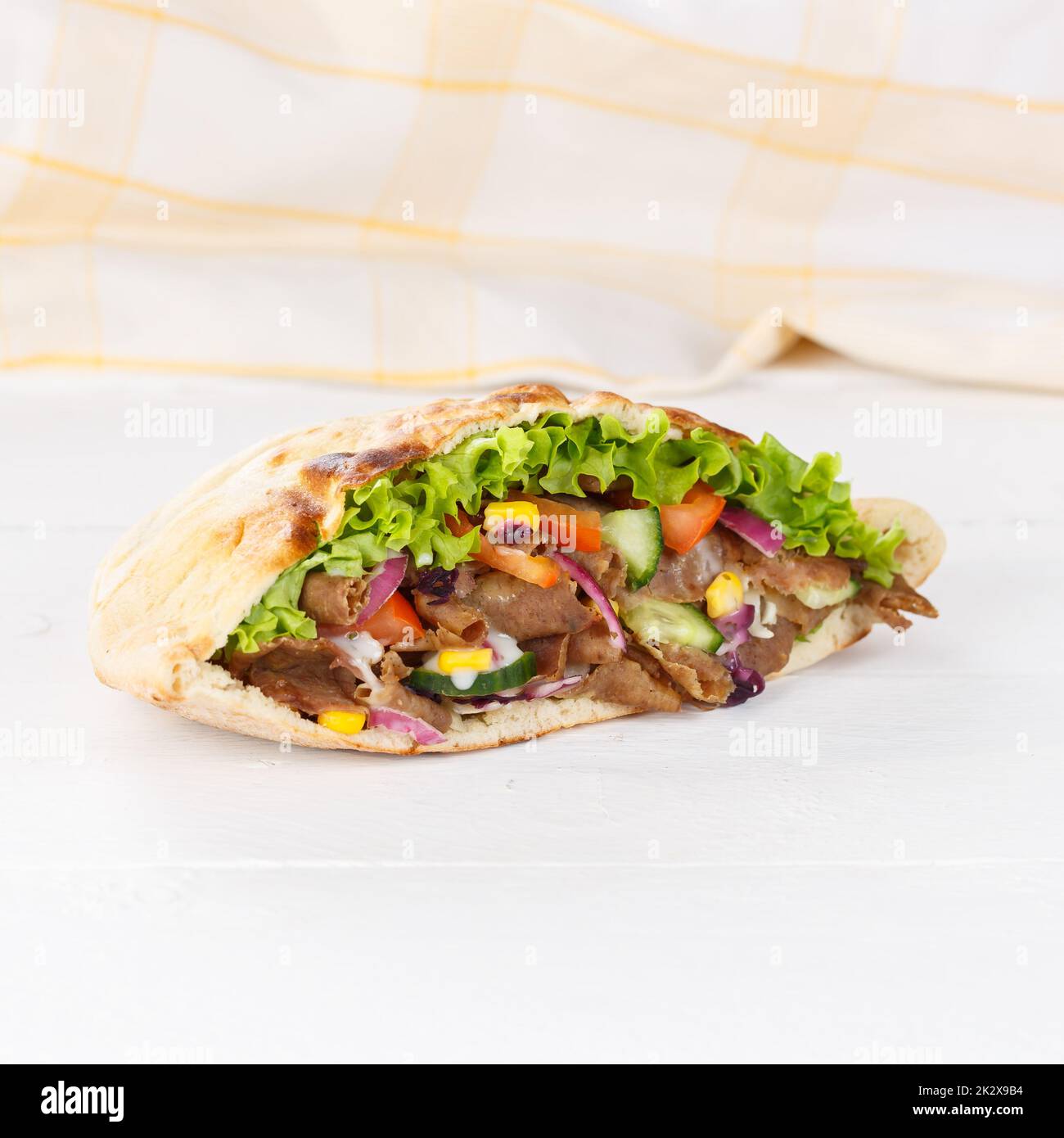 Döner Kebab Doner Kebap slice fast food in flatbread on a wooden board square sliced Stock Photo