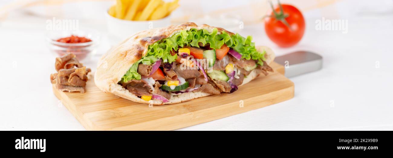 Döner Kebab Doner Kebap slice fast food in flatbread with French Fries on a wooden board panorama sliced Stock Photo