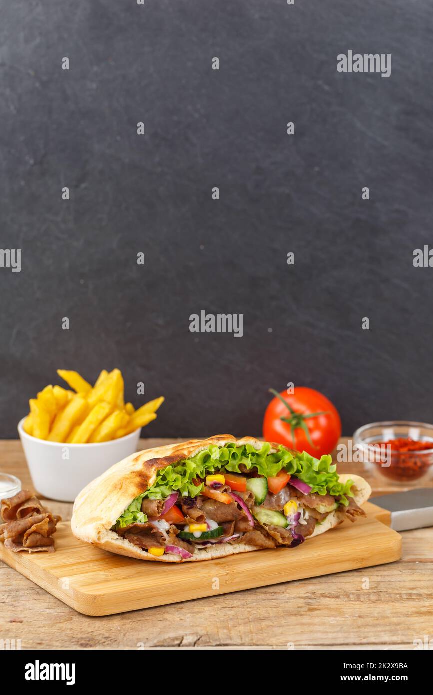Döner Kebab Doner Kebap slice fast food in flatbread with French Fries on a wooden board portrait format sliced Stock Photo