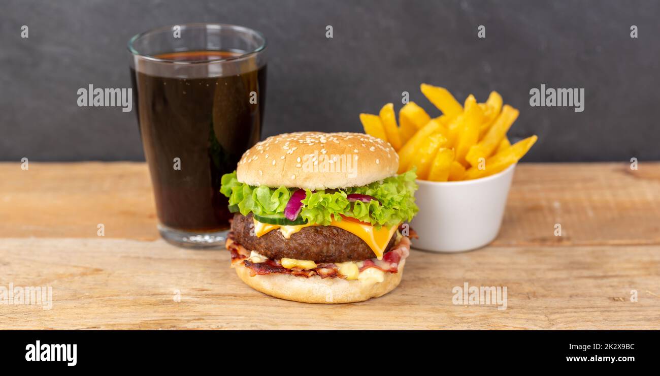 Hamburger Cheeseburger meal fastfood fast food with cola drink and French Fries on a wooden board panorama Stock Photo