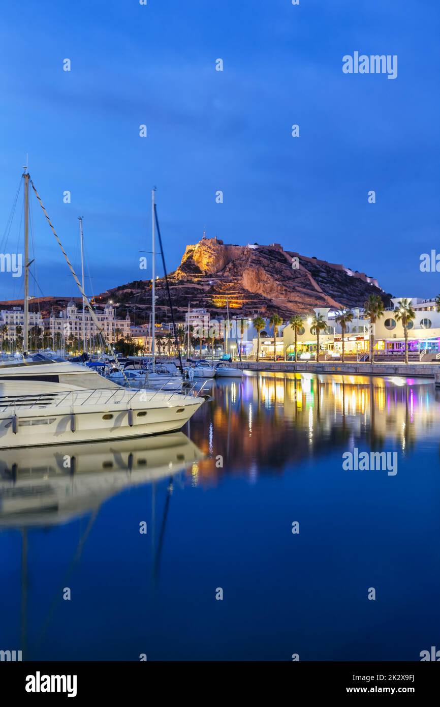 Alicante Port d'Alacant marina with boats and view of castle Castillo twilight travel traveling holidays vacation portrait format in Spain Stock Photo