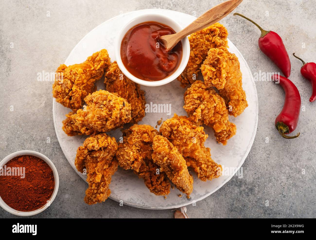 Spicy chicken wings breaded with spices and ketchup on the table. Stock Photo