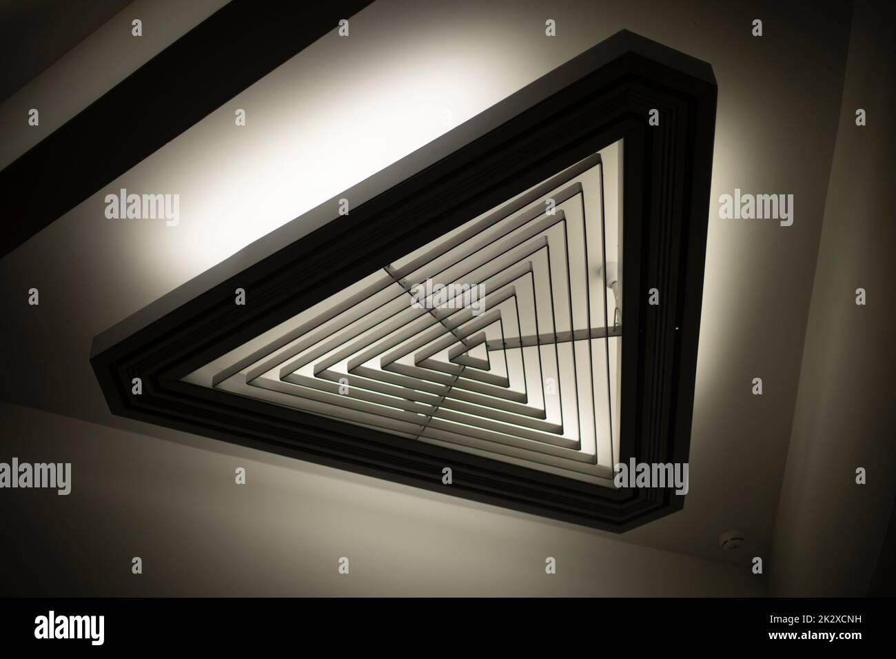 Triangular light source. Lamp in interior. Designer light. Architecture details. Stock Photo