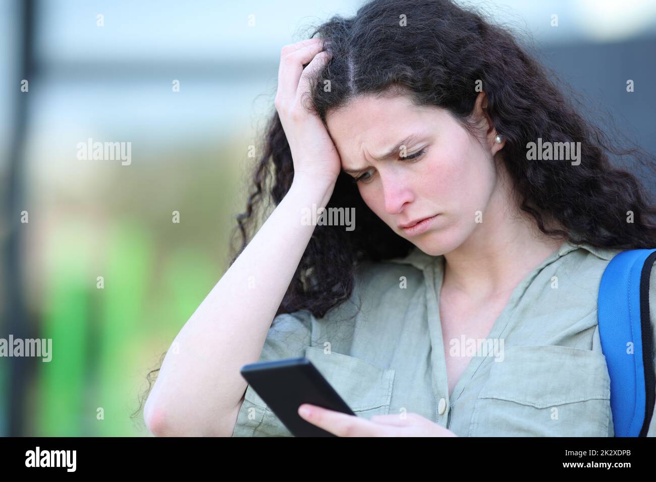 Sad student complaining reading message on phone Stock Photo