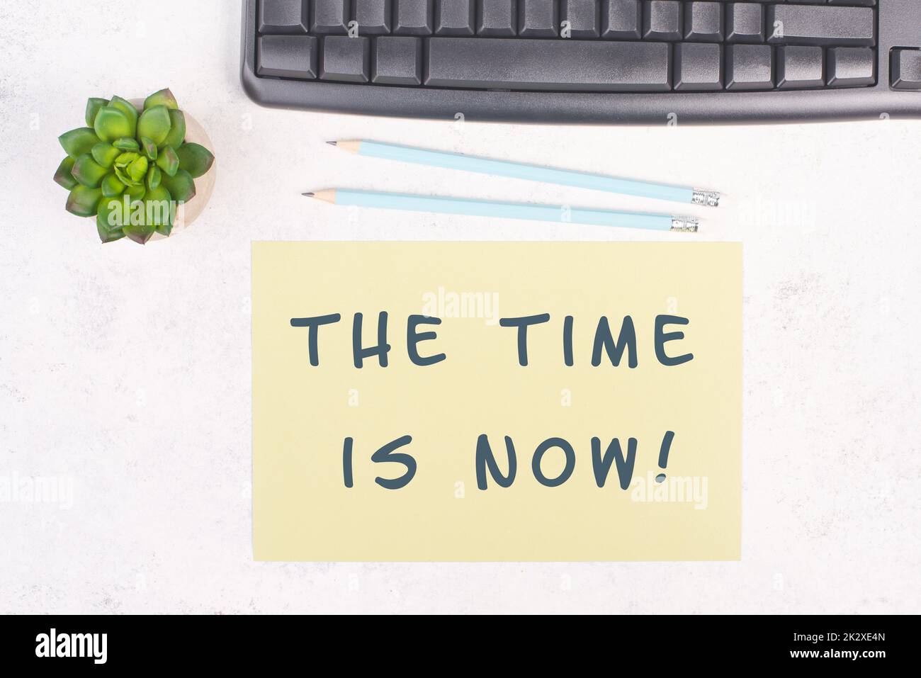 The phrase the time is now is standing on a paper, a pen, computer keyboard and a cactus, brainstorming for new business ideas, startup concept, home office desk Stock Photo