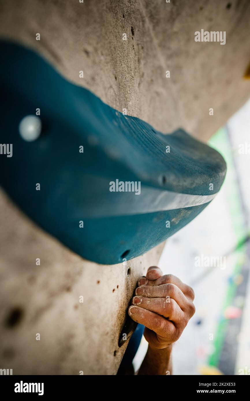 Male hand smeared with magnesium powder grabbing a hold of a climbing wall Stock Photo