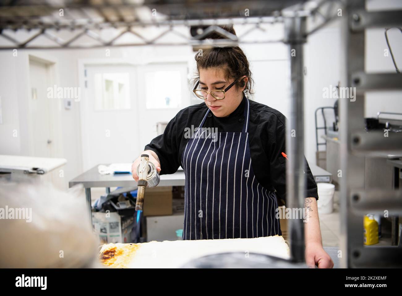 Female baker using blow torch in bakery kitchen Stock Photo Alamy
