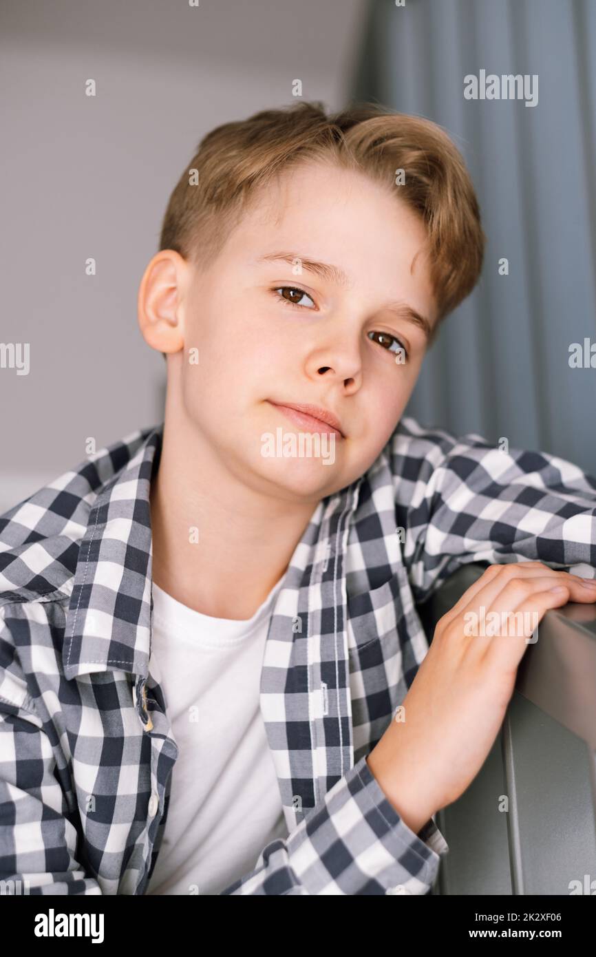 Close-up portrait of a modern teenager looking at the camera. The guy is sitting on the steps Stock Photo