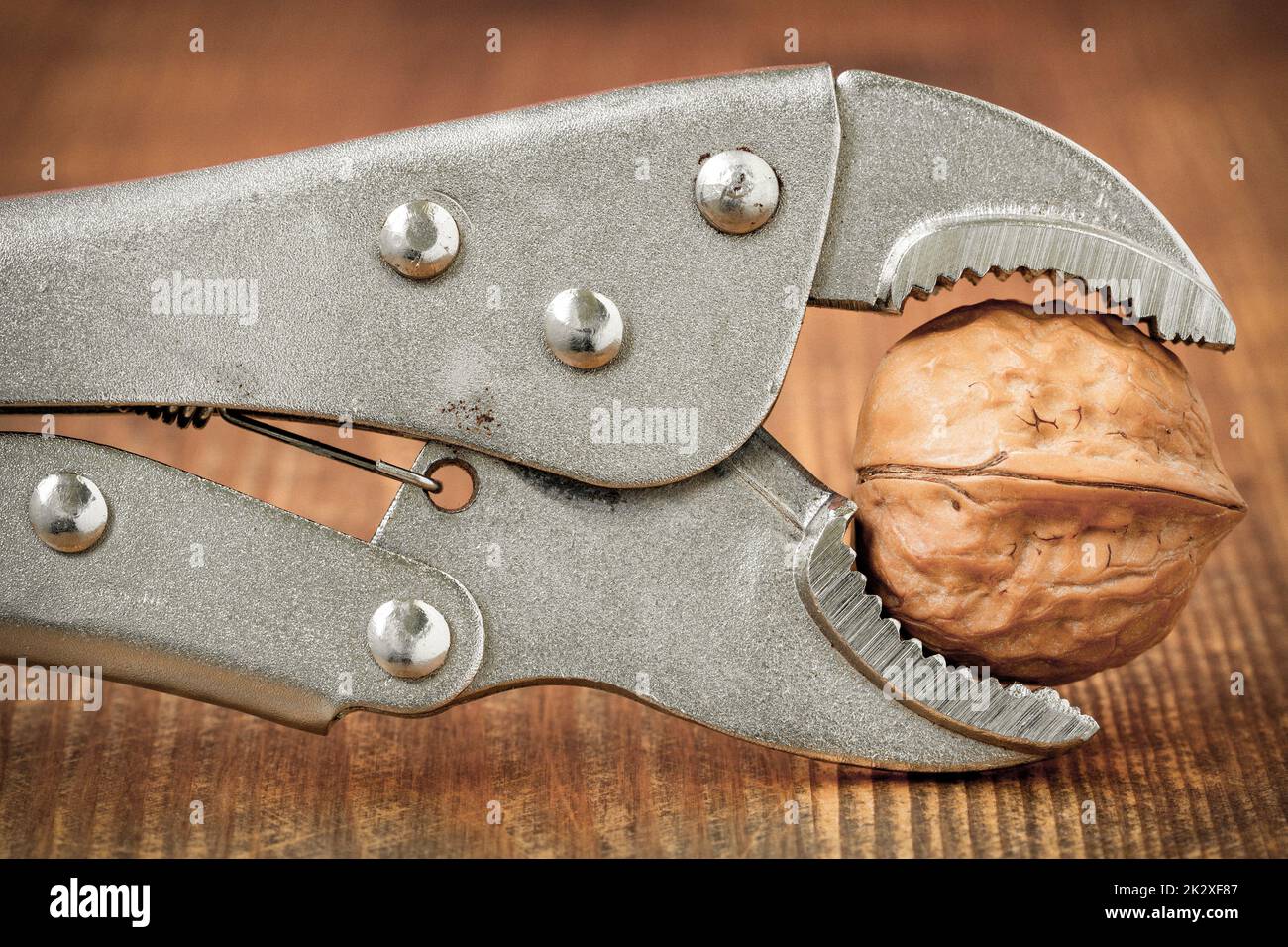 Adjustable wrench squeezing walnut to crack Stock Photo