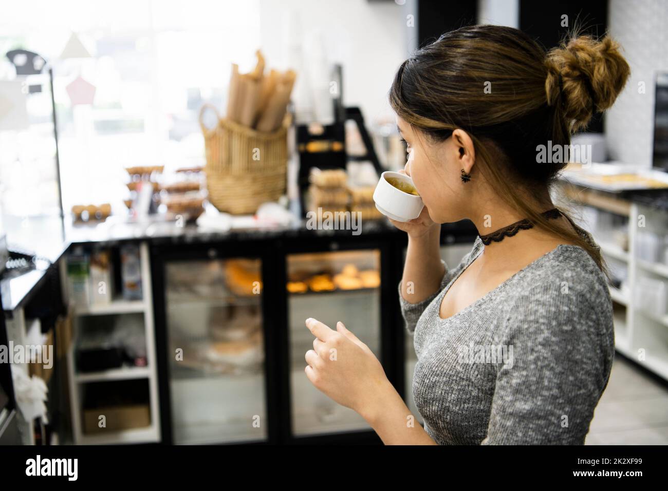 Female bakery owner drinking espresso behind counter Stock Photo Alamy