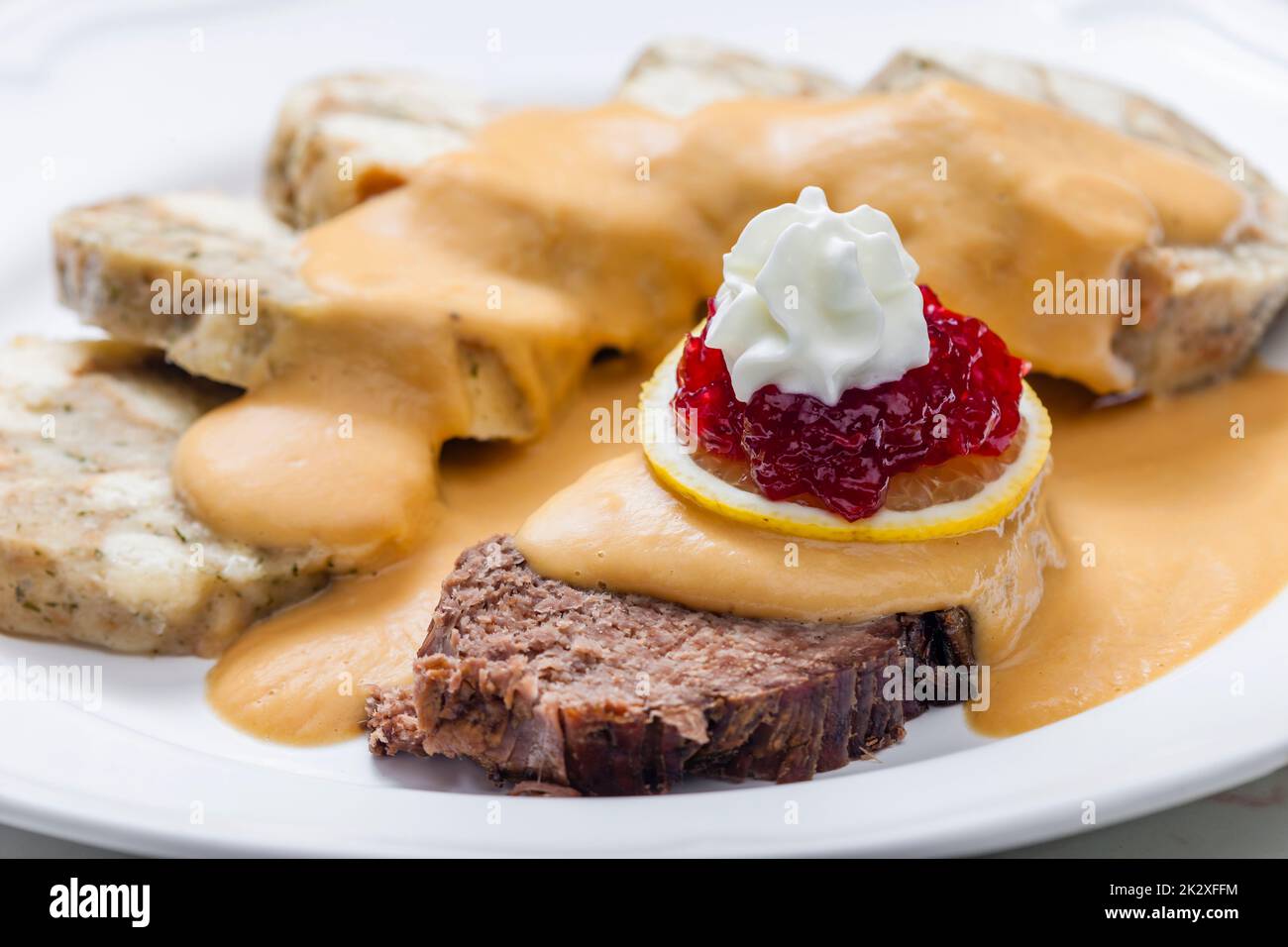 sirloin sauce with dumplings and cranberries on lemon with whipped cream Stock Photo
