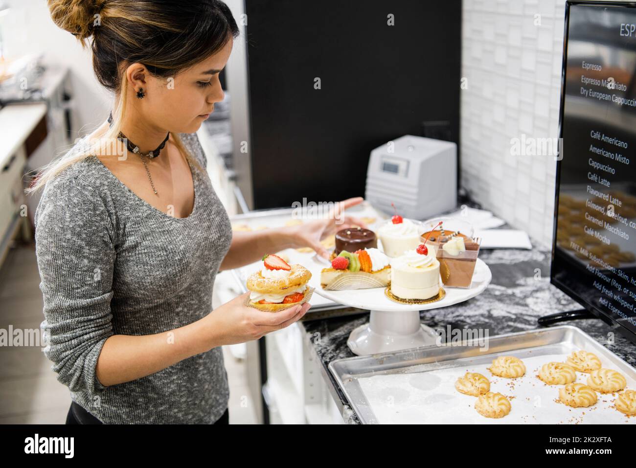 Female bakery owner arranging French pastries on cake stand Stock Photo Alamy