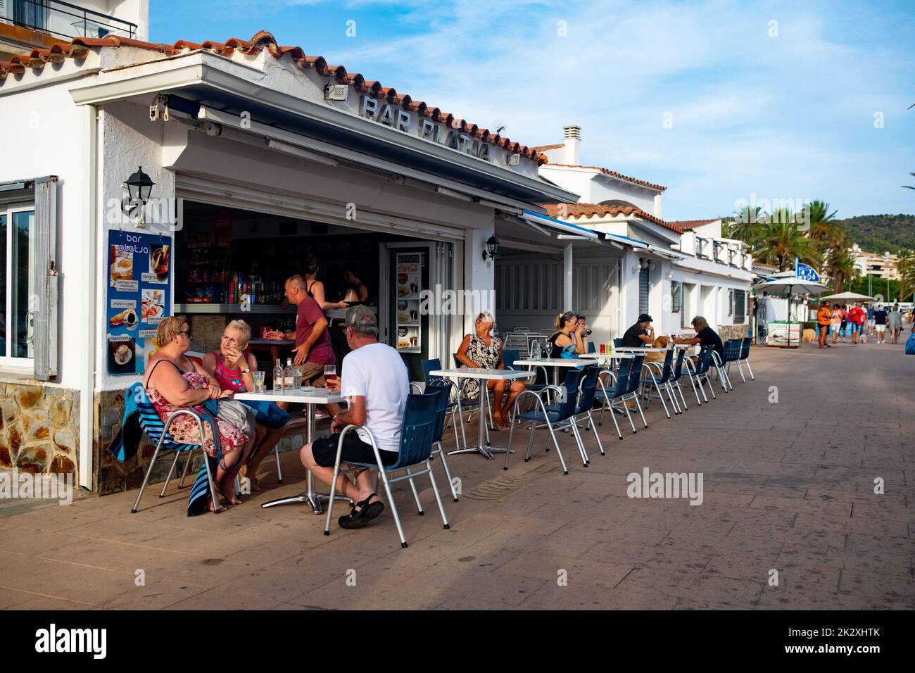 People walk and sit in bars along the promenade on the seafront of