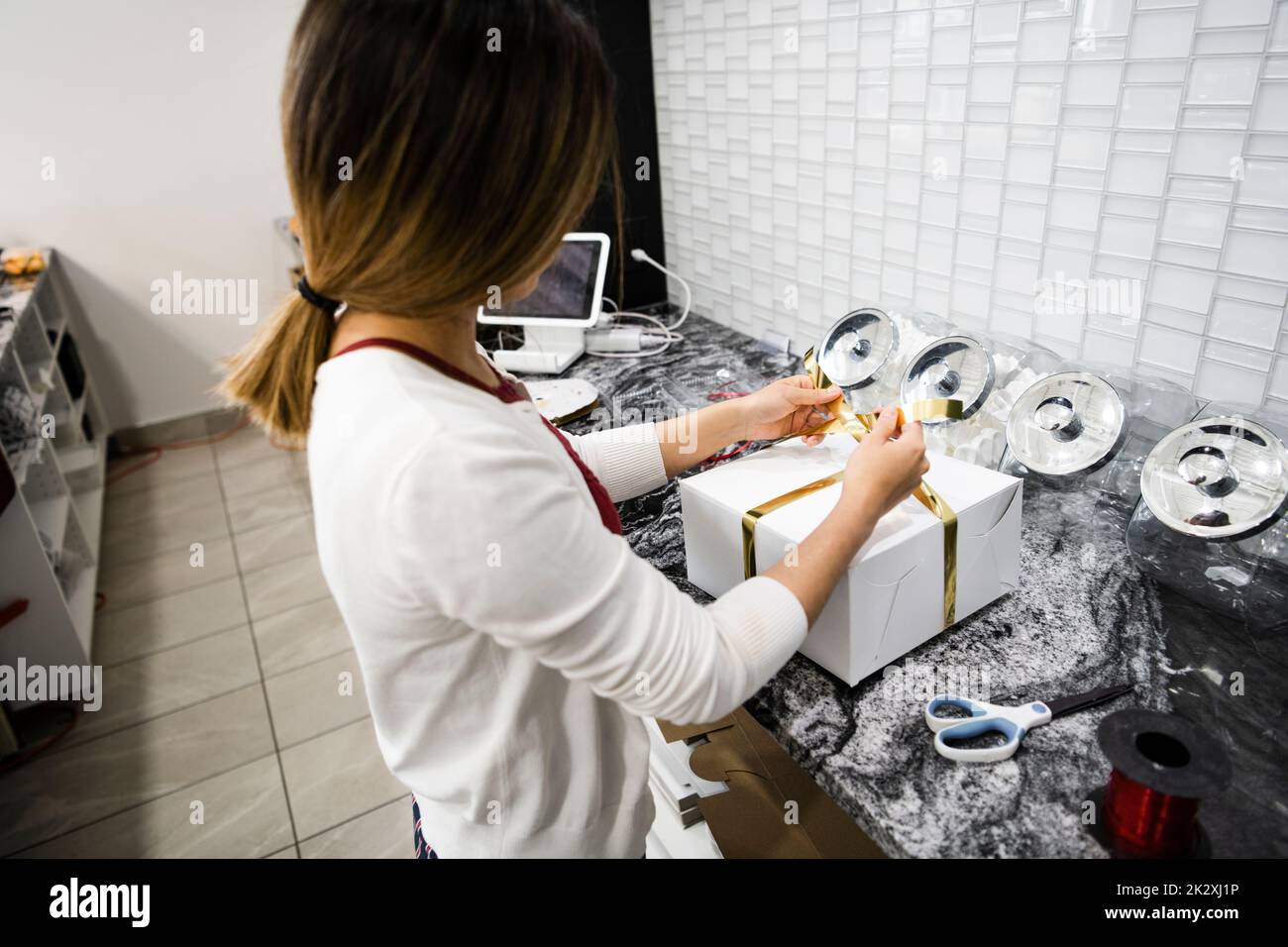 Female bakery owner tying ribbon around pastry box Stock Photo Alamy