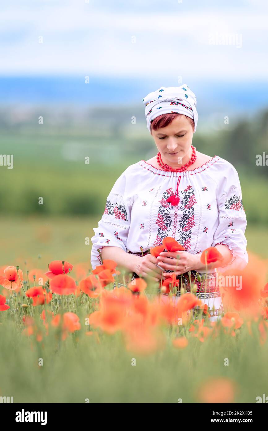 woman in Ukrainian national dress on a flowering poppy field Stock Photo