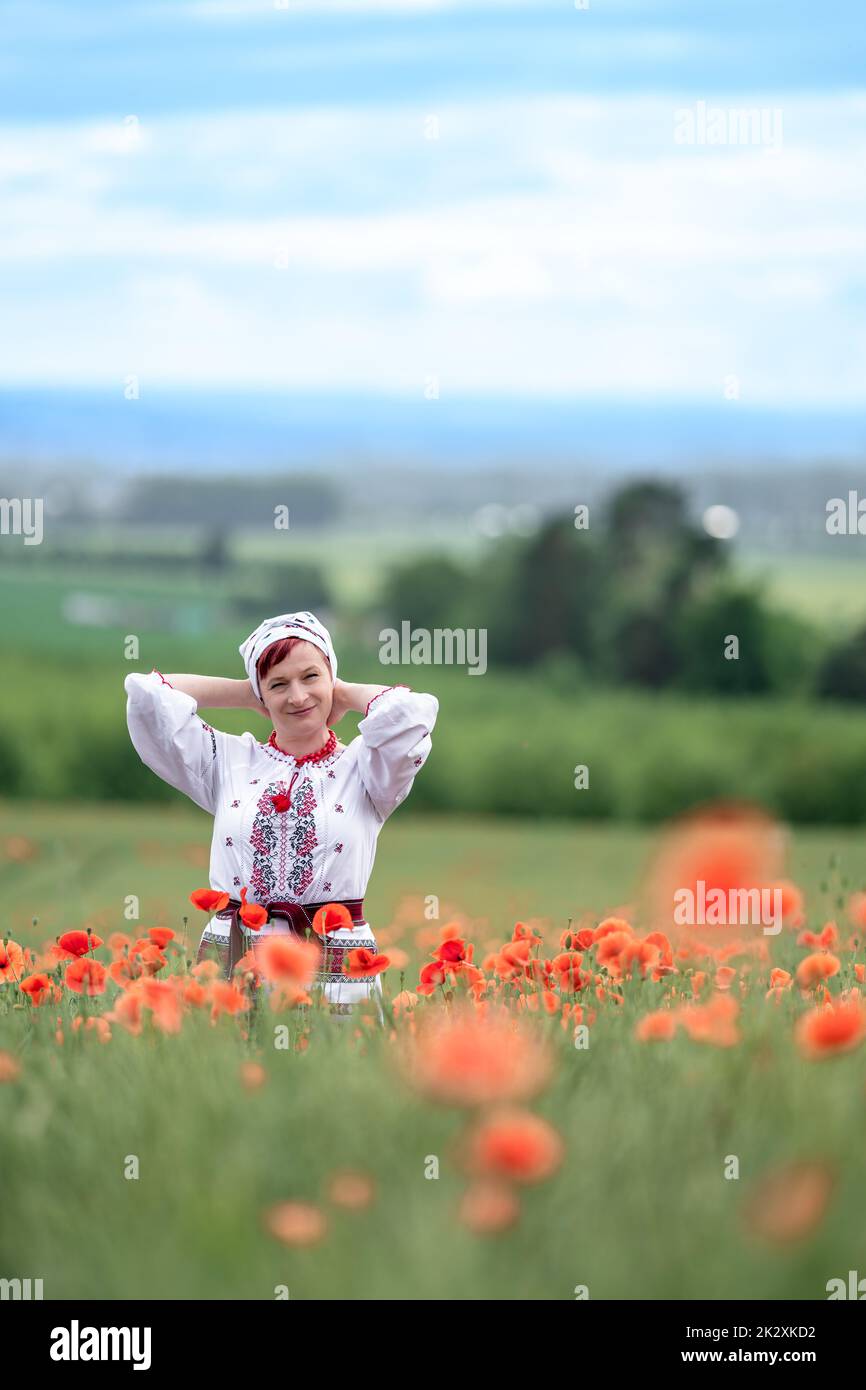 woman in Ukrainian national dress on a flowering poppy field Stock Photo