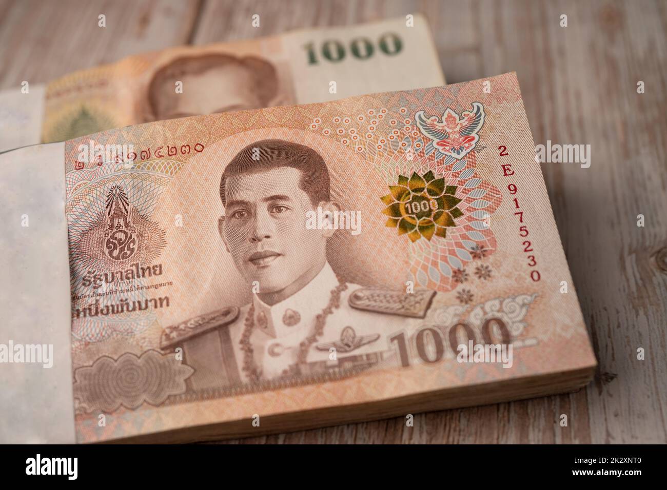 Stack of Thai baht banknotes on wooden background, business saving finance investment concept. Stock Photo