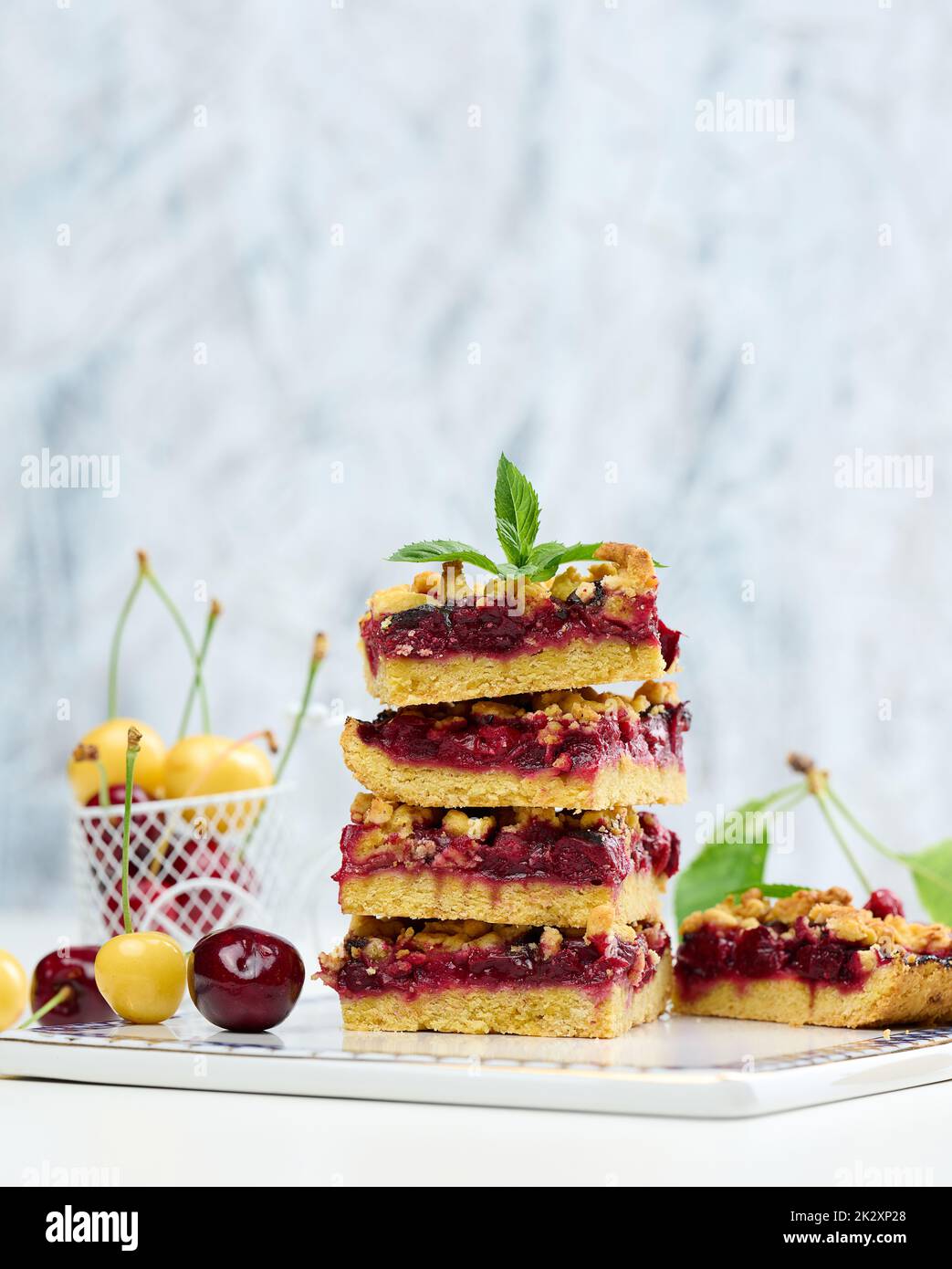 Square slices of cherry crumble lie in a stack on a white board Stock Photo