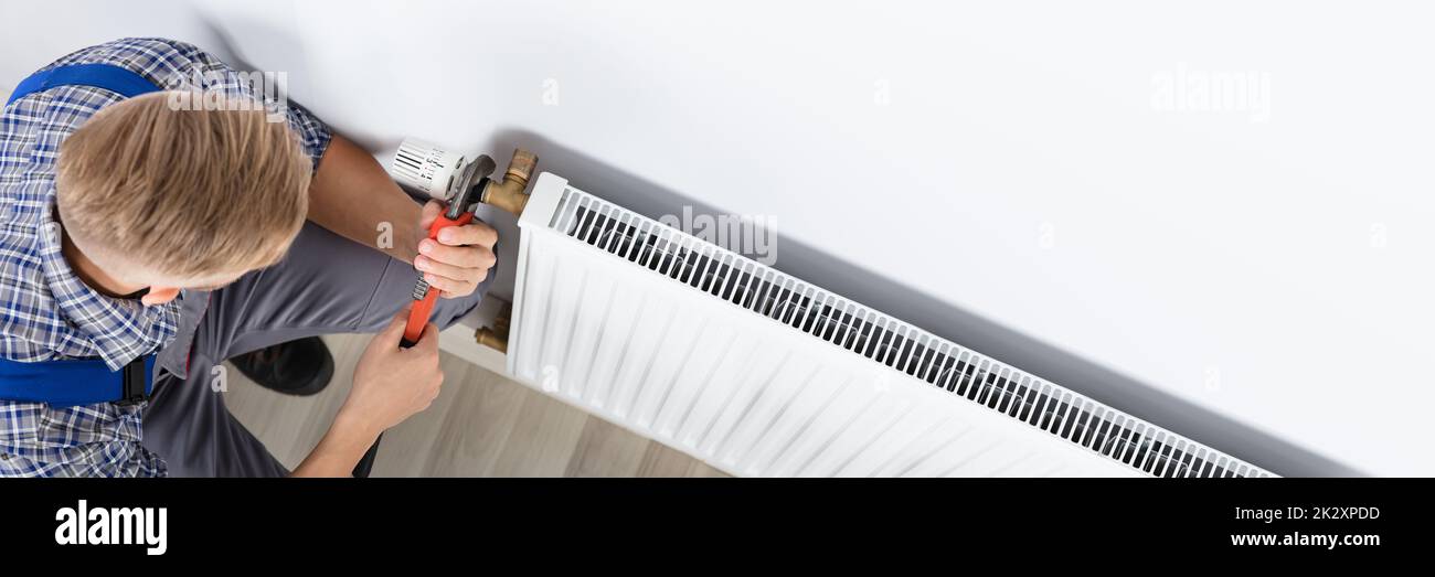 Male Plumber Fixing Thermostat Using Wrench Stock Photo