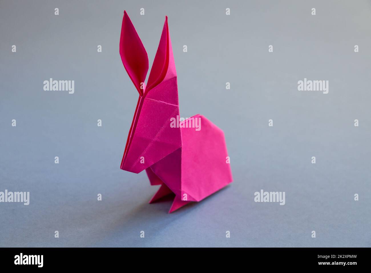 Pink paper rabbit origami isolated on a grey background Stock Photo