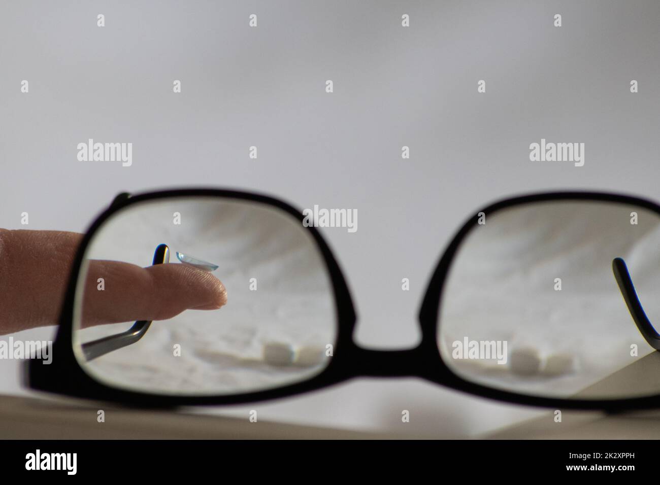 Blue contact lens through black eyeglasses shows different eyewear to correct farsightedness and nearsightedness by optometry or eye doctor against myopia with visual eye correction for perfect vision Stock Photo