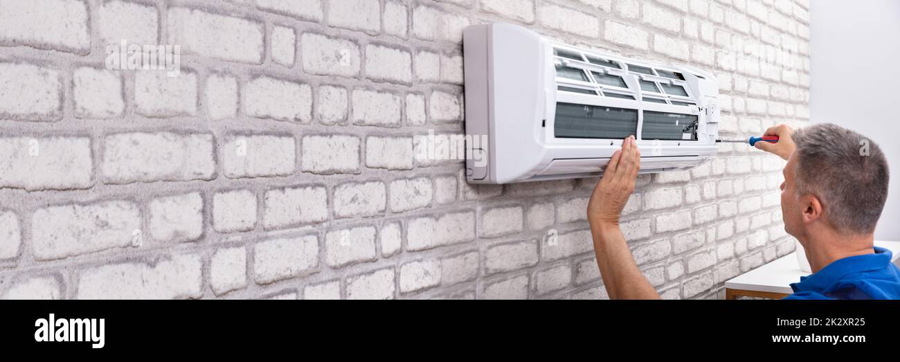Technician Fixing Air Conditioner Stock Photo