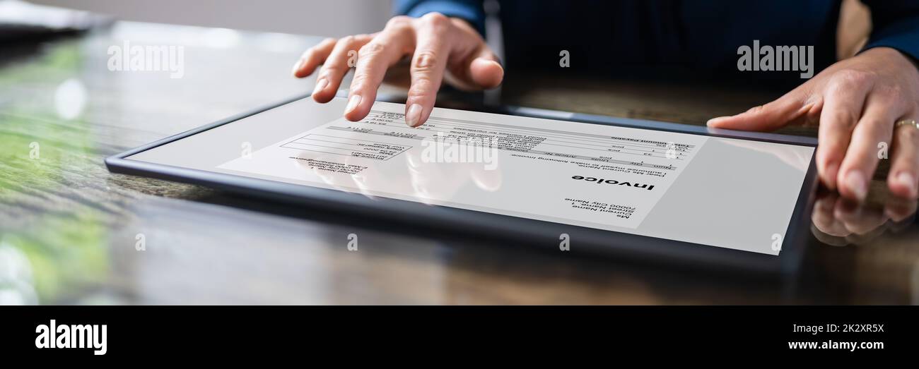 Businessperson Analyzing Invoice On Digital Tablet Stock Photo