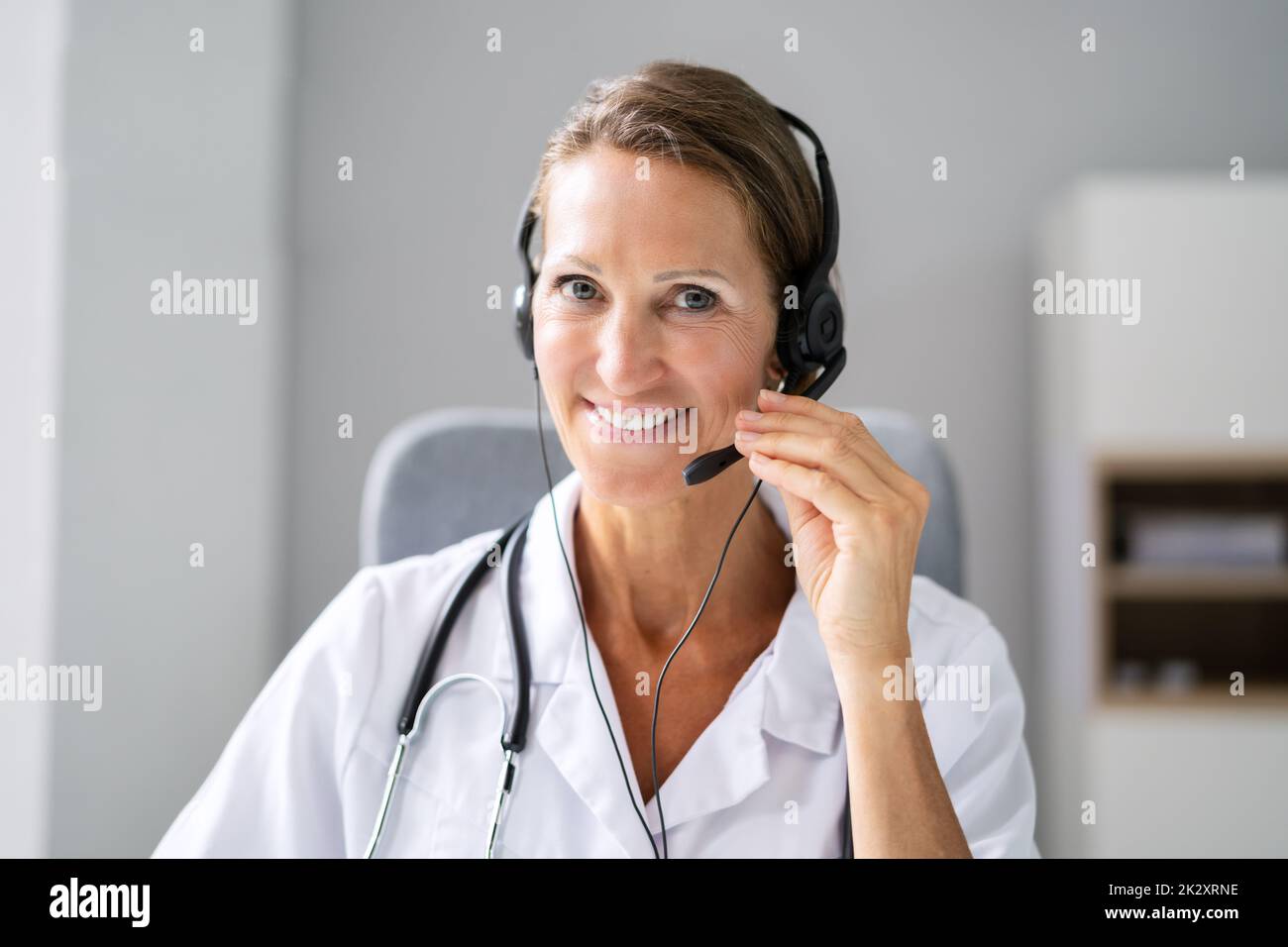 Confident Receptionist Using Headset In Hospital Stock Photo