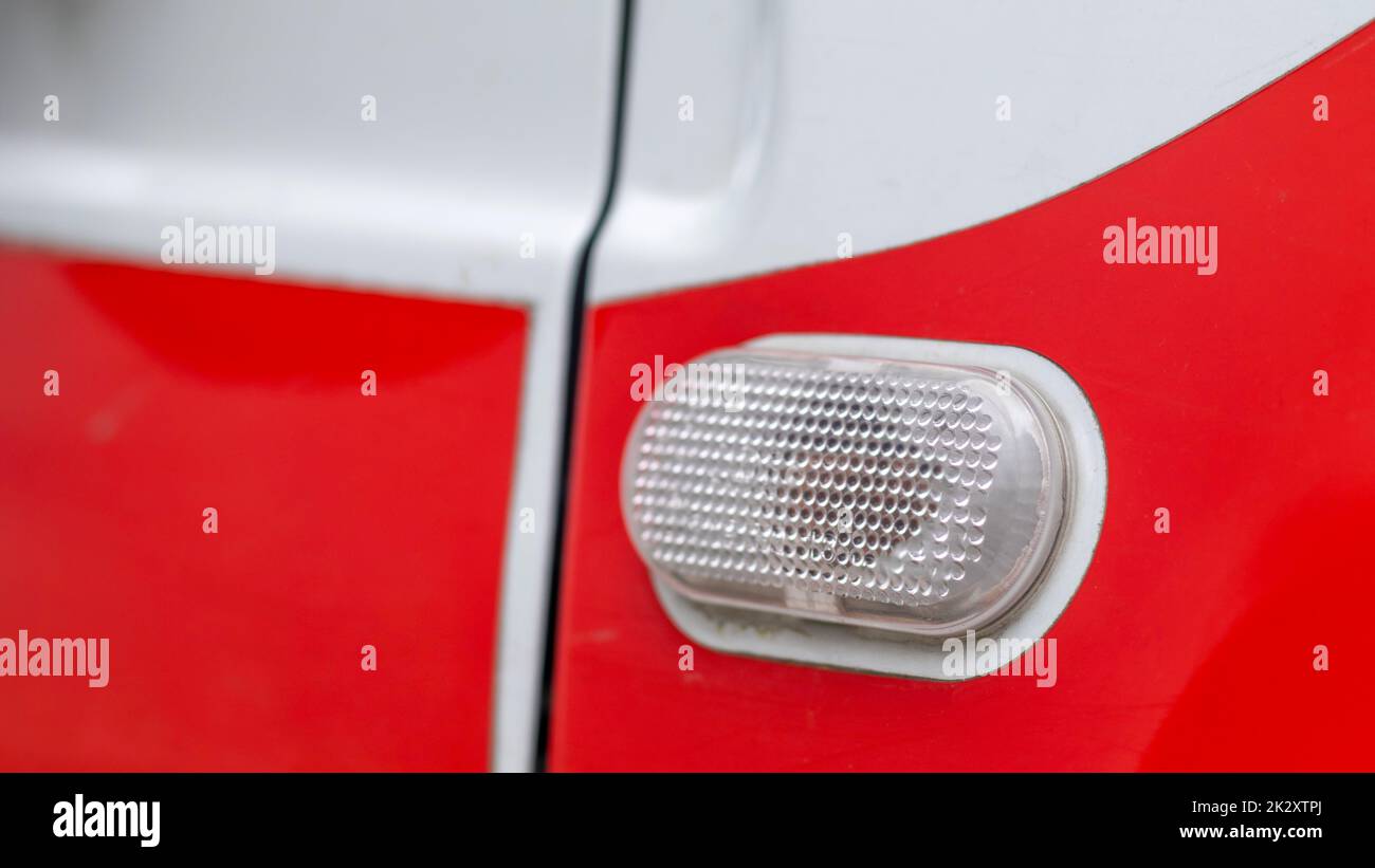 Automotive light bulb. Turn signal on the side of the car. A white turn signal on a red crossover, which is located on the side on the right side of the fender surface. Stock Photo
