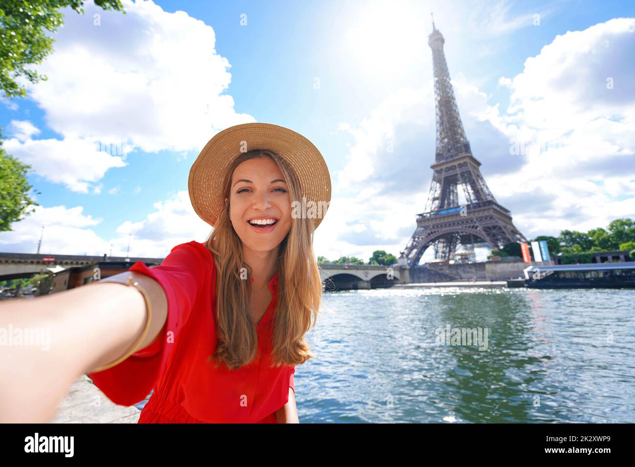 Young tourist woman making selfie photo with Eiffel tower on the background in sunny day in Paris, France Stock Photo