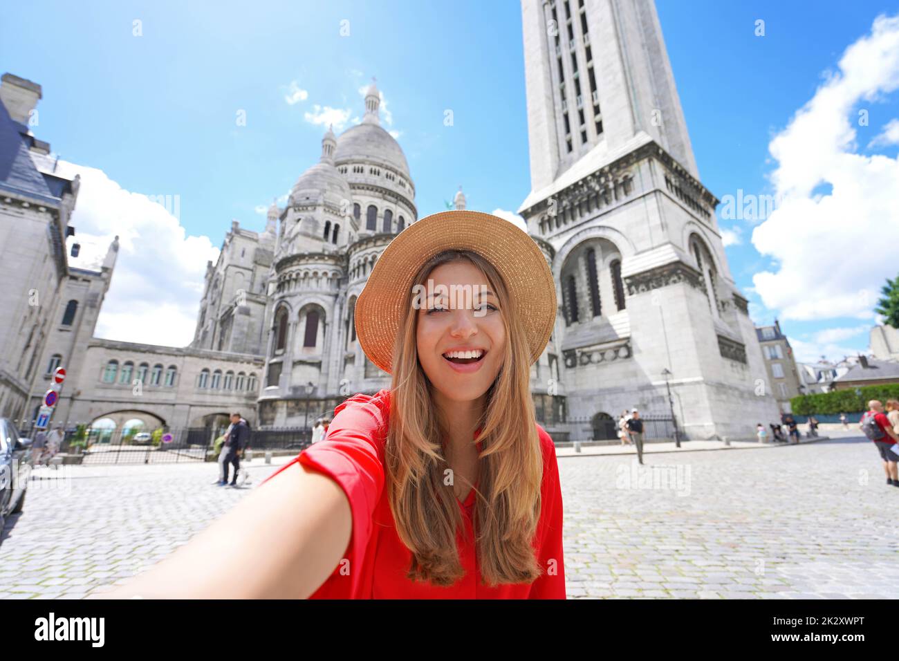 Selfie girl in Paris with the Basilica of the Sacred Heart of Paris on the background. Smiling at camera. Low angle. Stock Photo