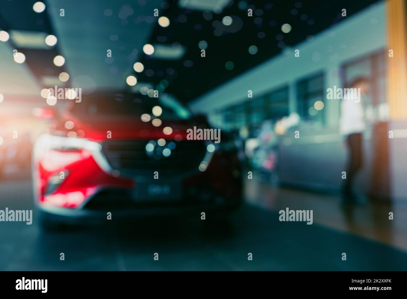 Blurred photo new red car parked in showroom. Car dealership office. Car parked in showroom with care. Auto for sale and rent business. Automobile leasing market. Electric vehicle. Luxury car company. Stock Photo