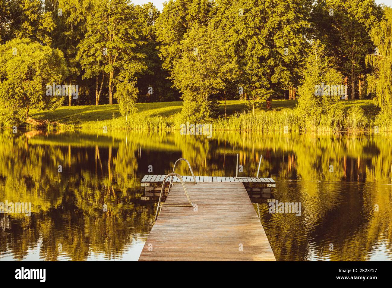 Empty wooden pier on a quiet lake in the morning Stock Photo