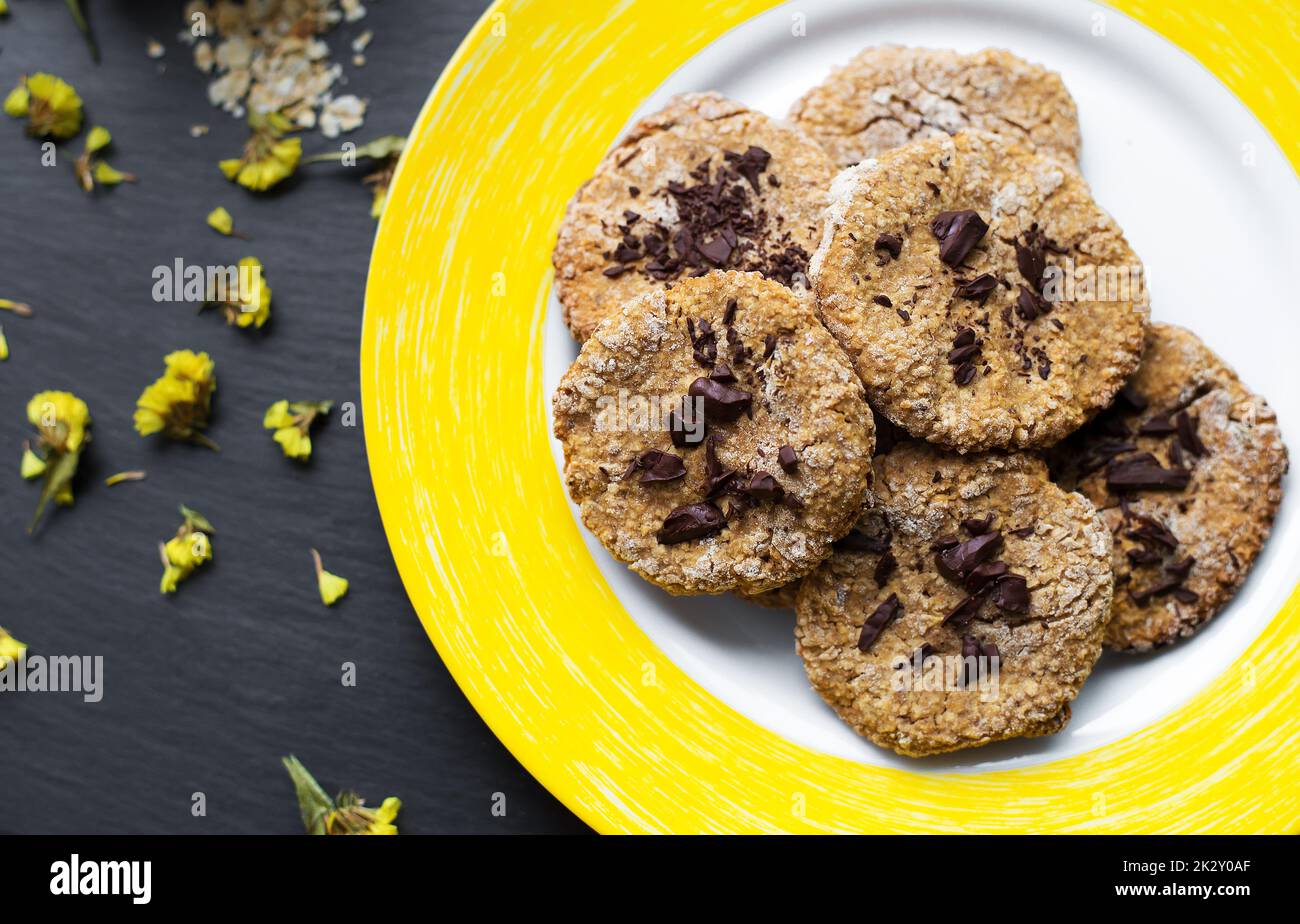 Oatmeal cookies with chocolate on yellow plate Stock Photo