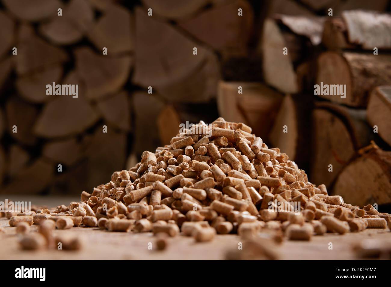 Pile of wooden pellets near stack of firewood in daylight Stock Photo