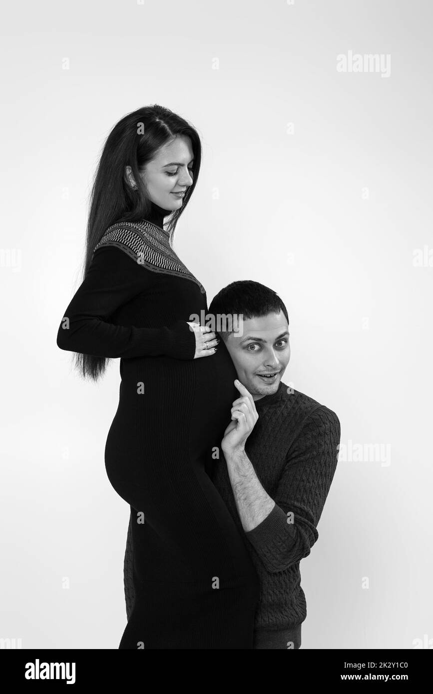man listening to his young beautiful pregnant wife's tummy Stock Photo