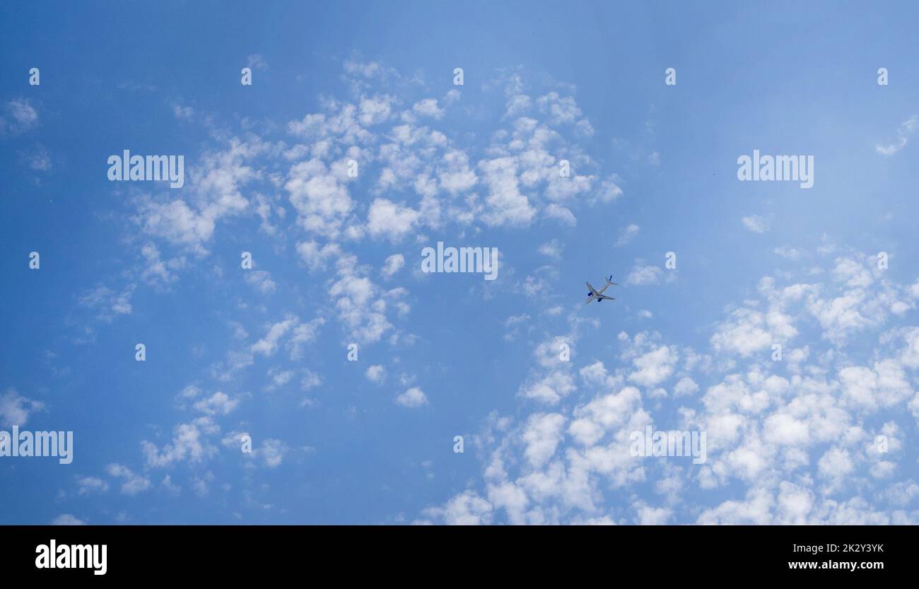 The plane is flying in a blue sky among clouds and sunlight, a copy of space Stock Photo