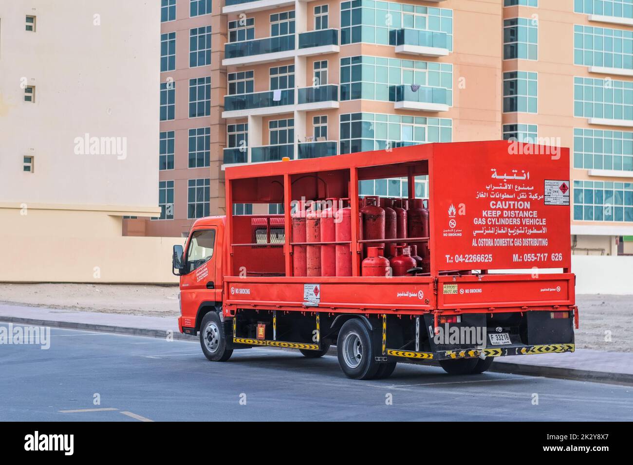 Red delivery lorry with red gas cylinders for home residential households. Gas utility municipal service. Dubai, UAE Stock Photo
