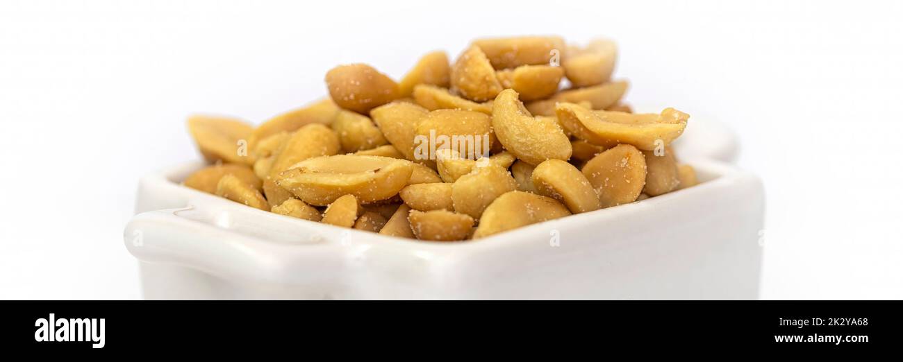 Panorama of roasted salted peanuts in a white square bowl.  Isolated against a white background. Stock Photo