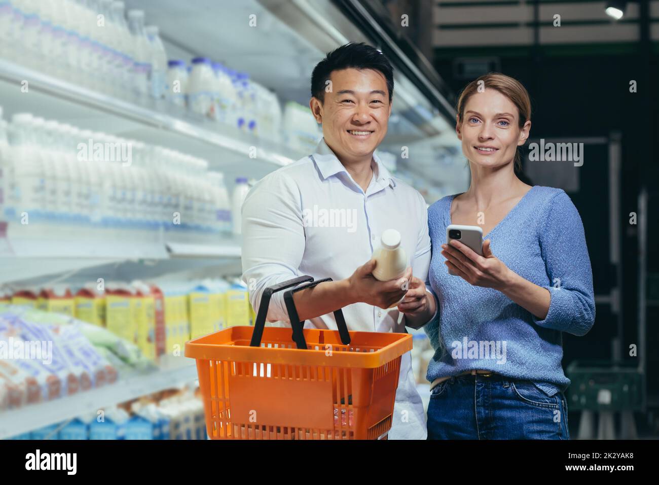Portrait of a happy Asian couple of consumers, supermarket shoppers or grocery store looking at camera smiling. Glad. man and woman together. Close young wife and husband. Family shopping. indoors Stock Photo