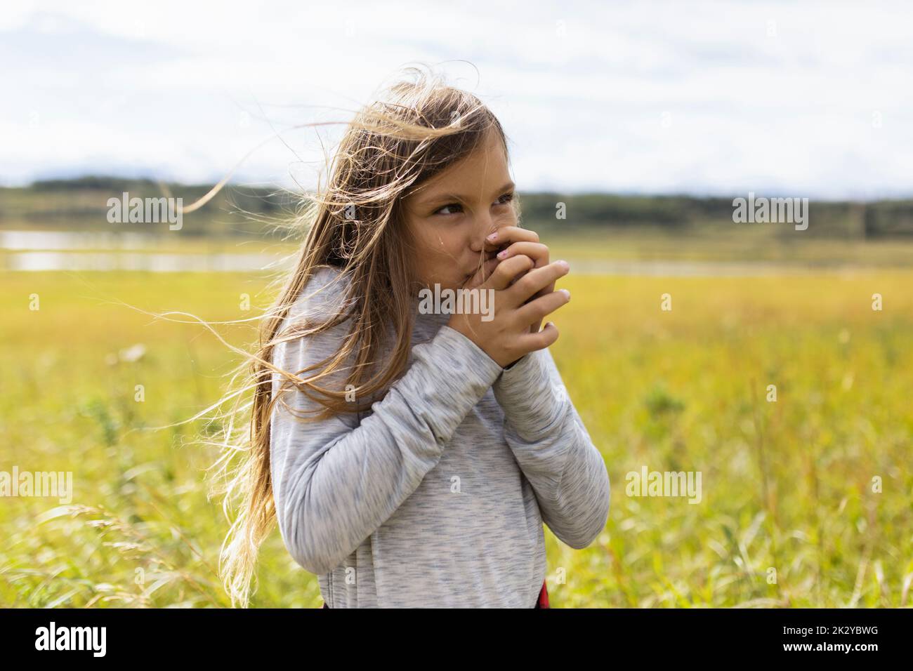 Girl with grass whistle in sunny rural farm field Stock Photo Alamy