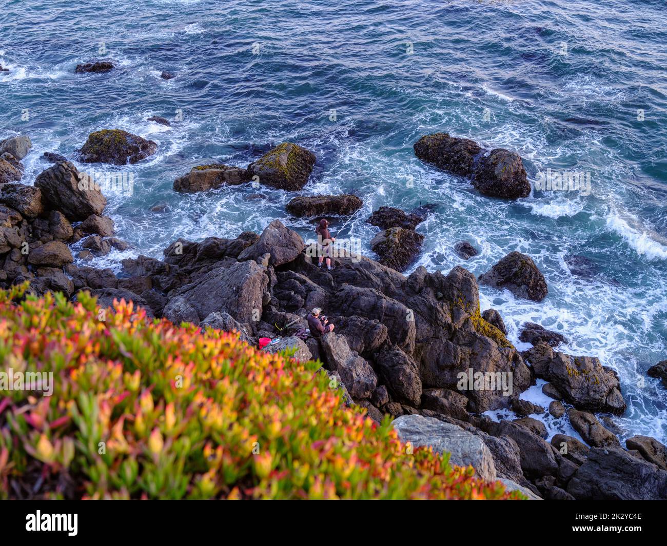 Two anglers fishing from  a rocky cliffside, Bodega Bay, California Stock Photo