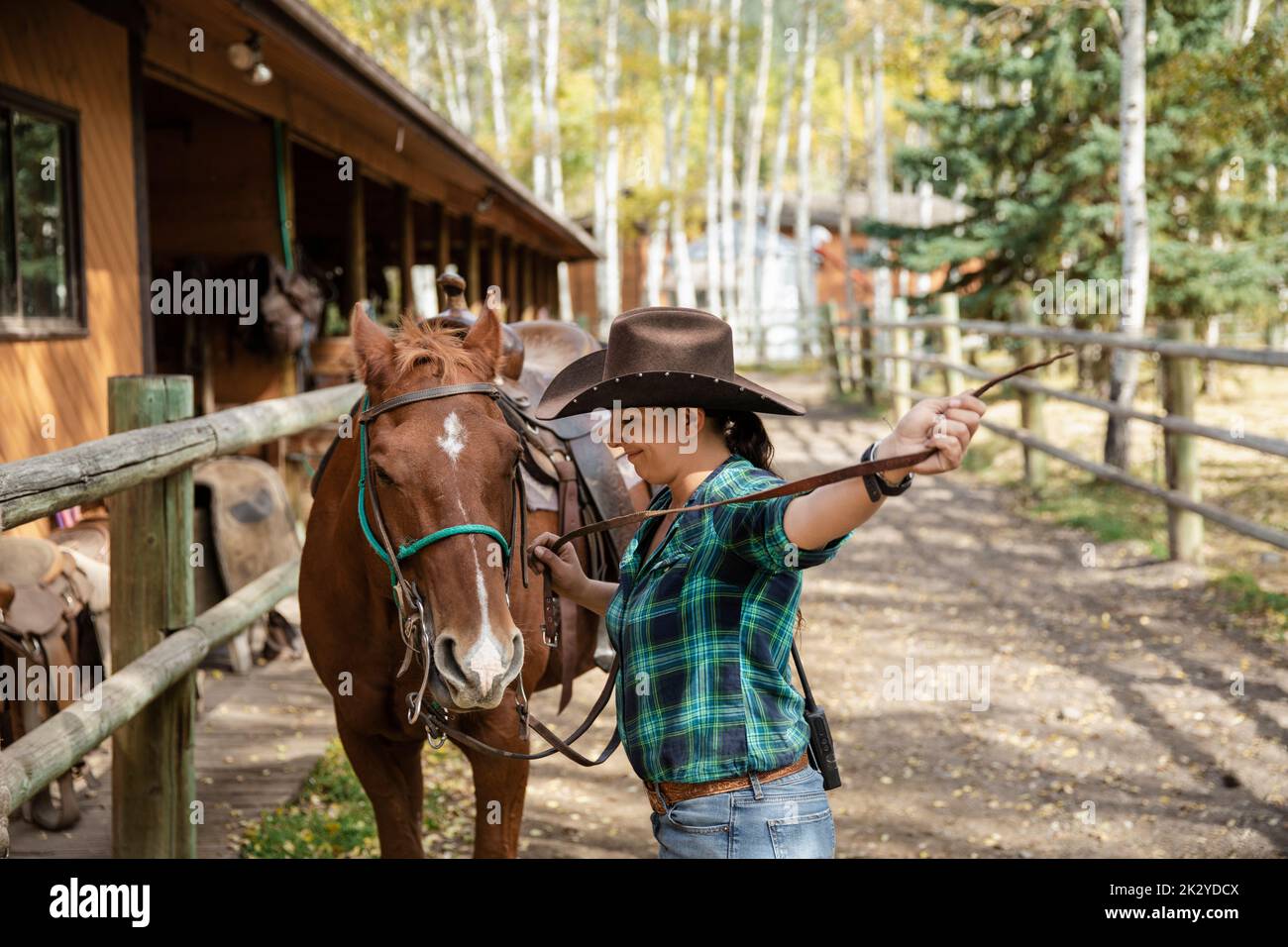 Female rancher with saddled horse on rural ranch Stock Photo Alamy