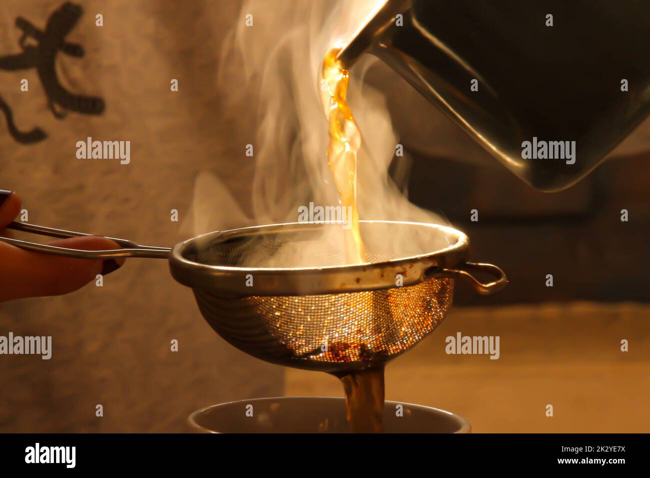 Pouring tea in a cup with a strainer Stock Photo