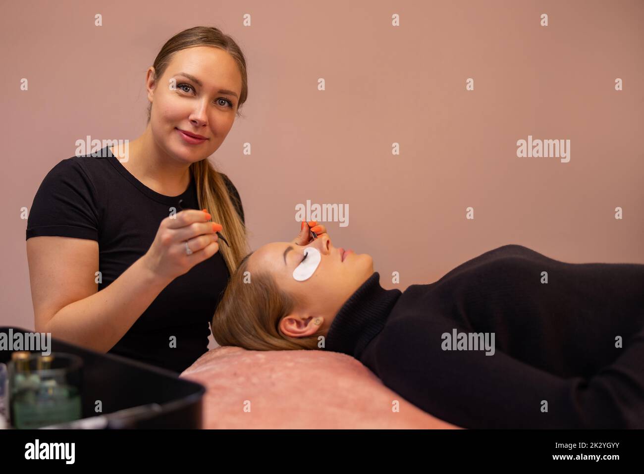 Confident Smiling Expert By Female Customer During Eyelash Extension Stock Photo