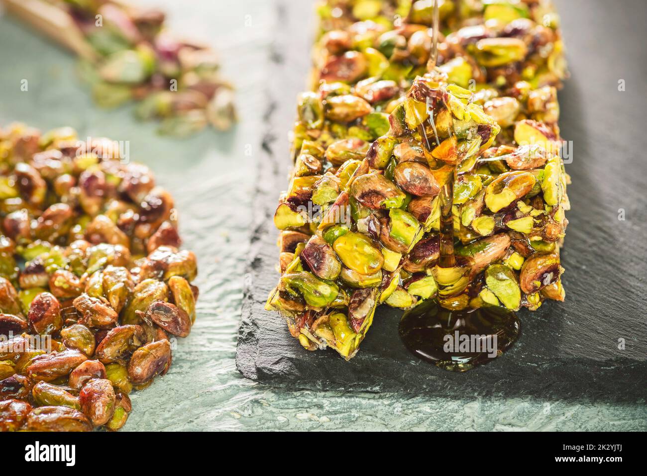 Pouring honey on traditional sugar coated pistachio sweets. Egyptian oriental dessert usually eaten during 'Prophet Muhammad Birthday Celebration'. Stock Photo