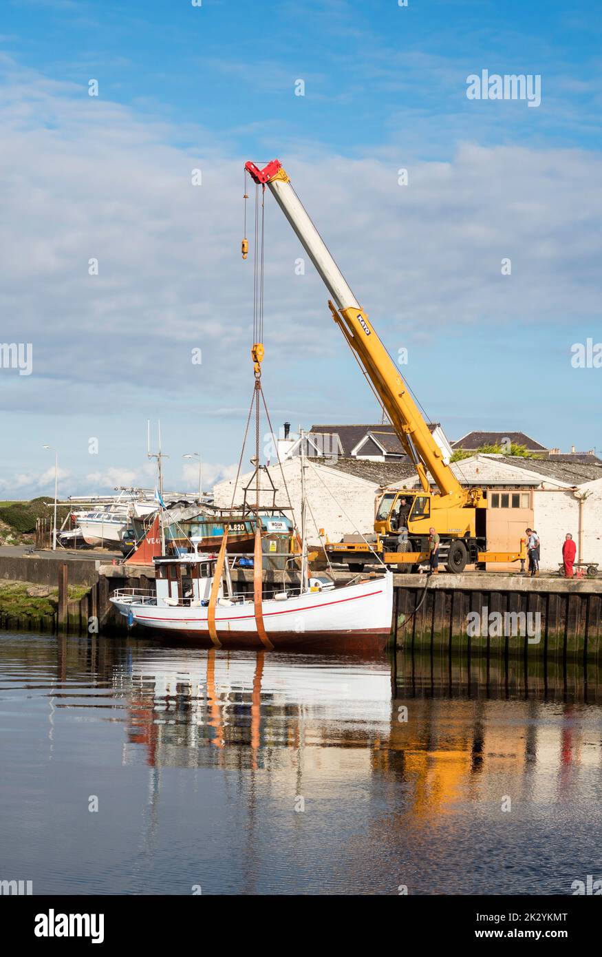 Kato Crane preparing to lift a vintage fishing boat out of the water in Girvan harbour, South Ayrshire, Scotland, UK Stock Photo