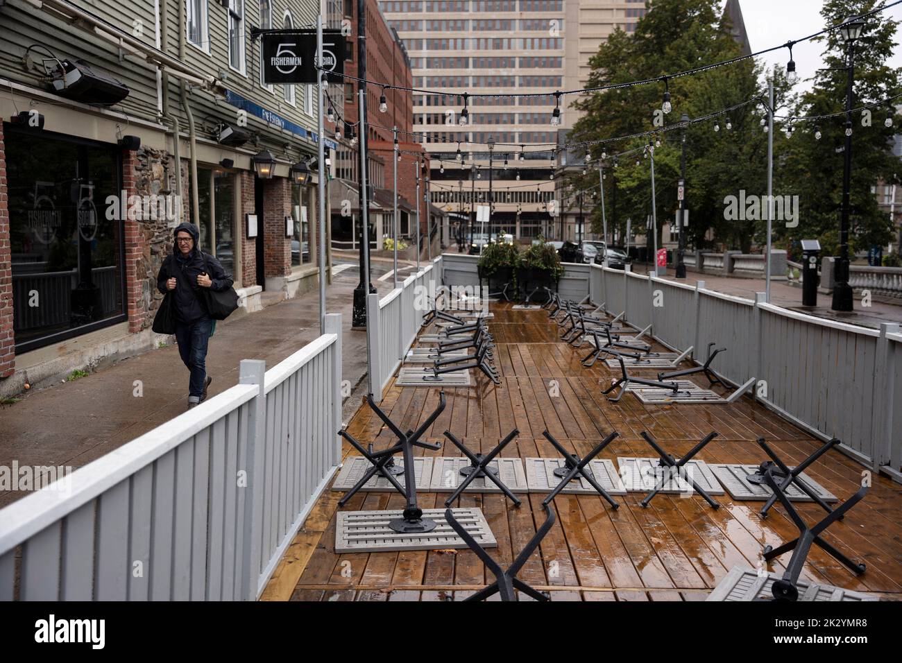 Canada. 23rd Sep, 2022. Restaurant tables are turned upside down as a pedestrian walks past the patio in downtown Halifax ahead of Hurricane Fiona making landfall on Friday, Sept. 23, 2022. THE CANADIAN PRESS/Darren Calabrese Credit: The Canadian Press/Alamy Live News Stock Photo