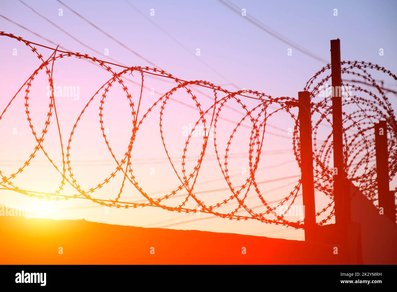 Fence with barbed wire background bright red setting sun Stock Photo ...